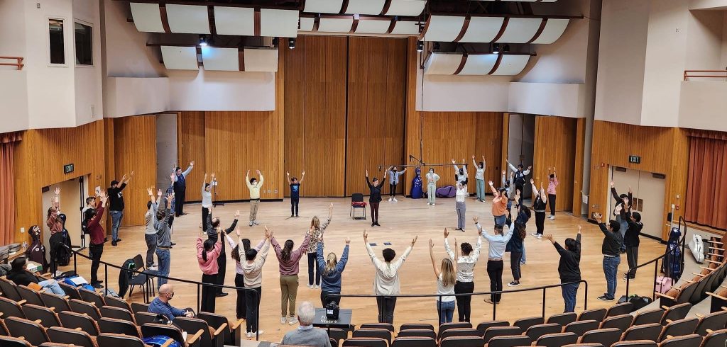 Students in a concert hall doing a Pilates exercise